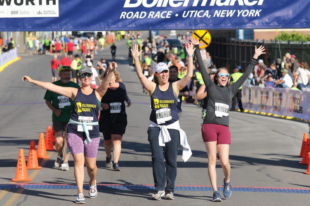 Happy runners raise their arms in celebration as they cross the finish line of the Boilermaker 5K.