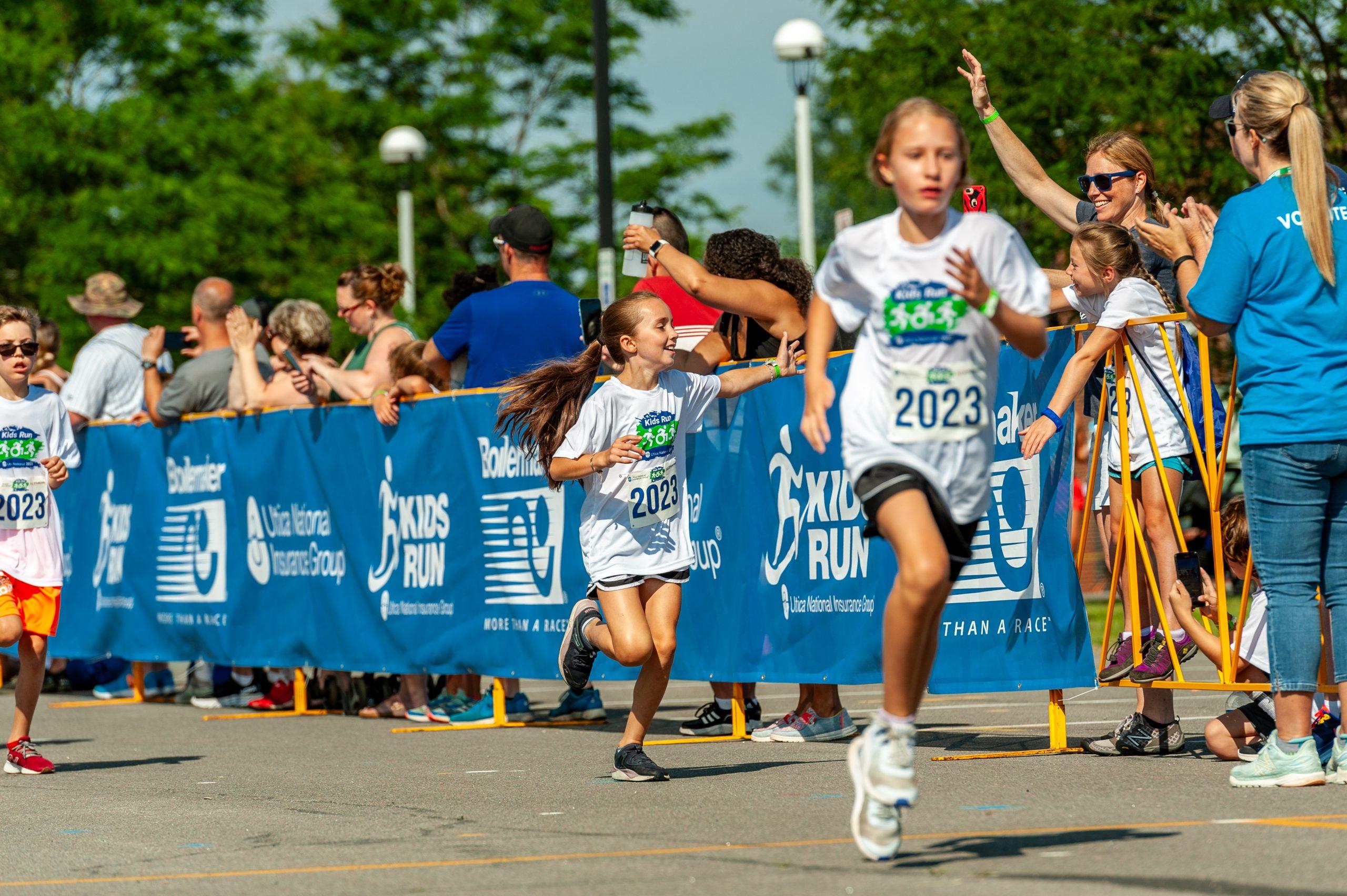 A child waves while running the Boilermaker 2023 Kids Run.