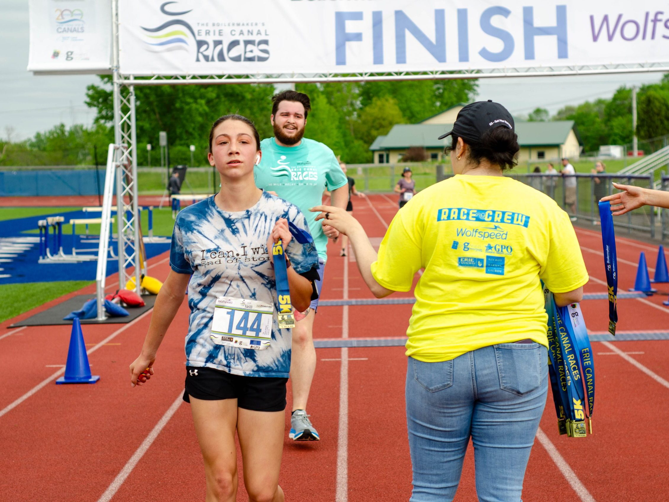 Runners at the Erie Canal Races receive medals after crossing the finish line