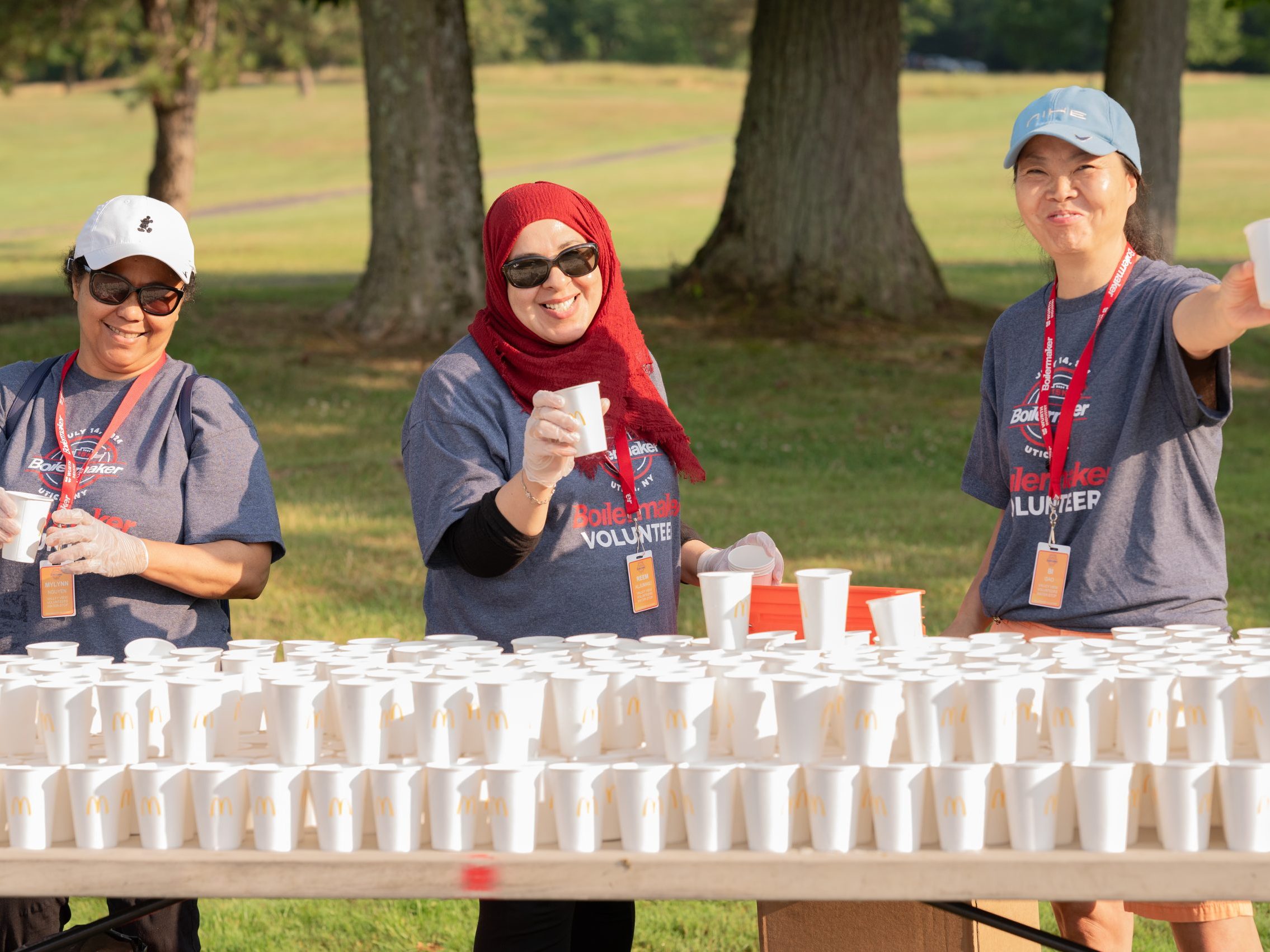 Boilermaker volunteers hold up water cups at a water station along the Boilermaker course