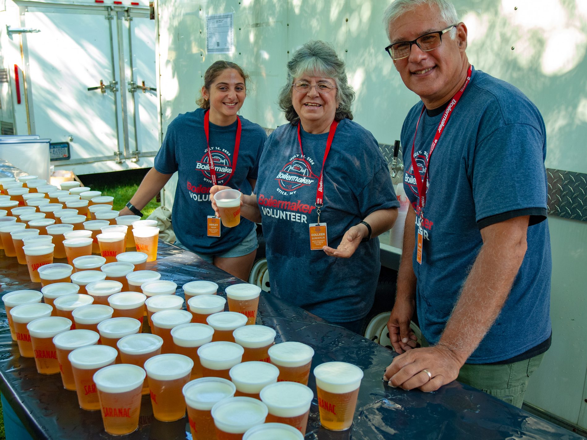 Volunteers smile while serving Utica Club at the Boilermaker Post Race Party