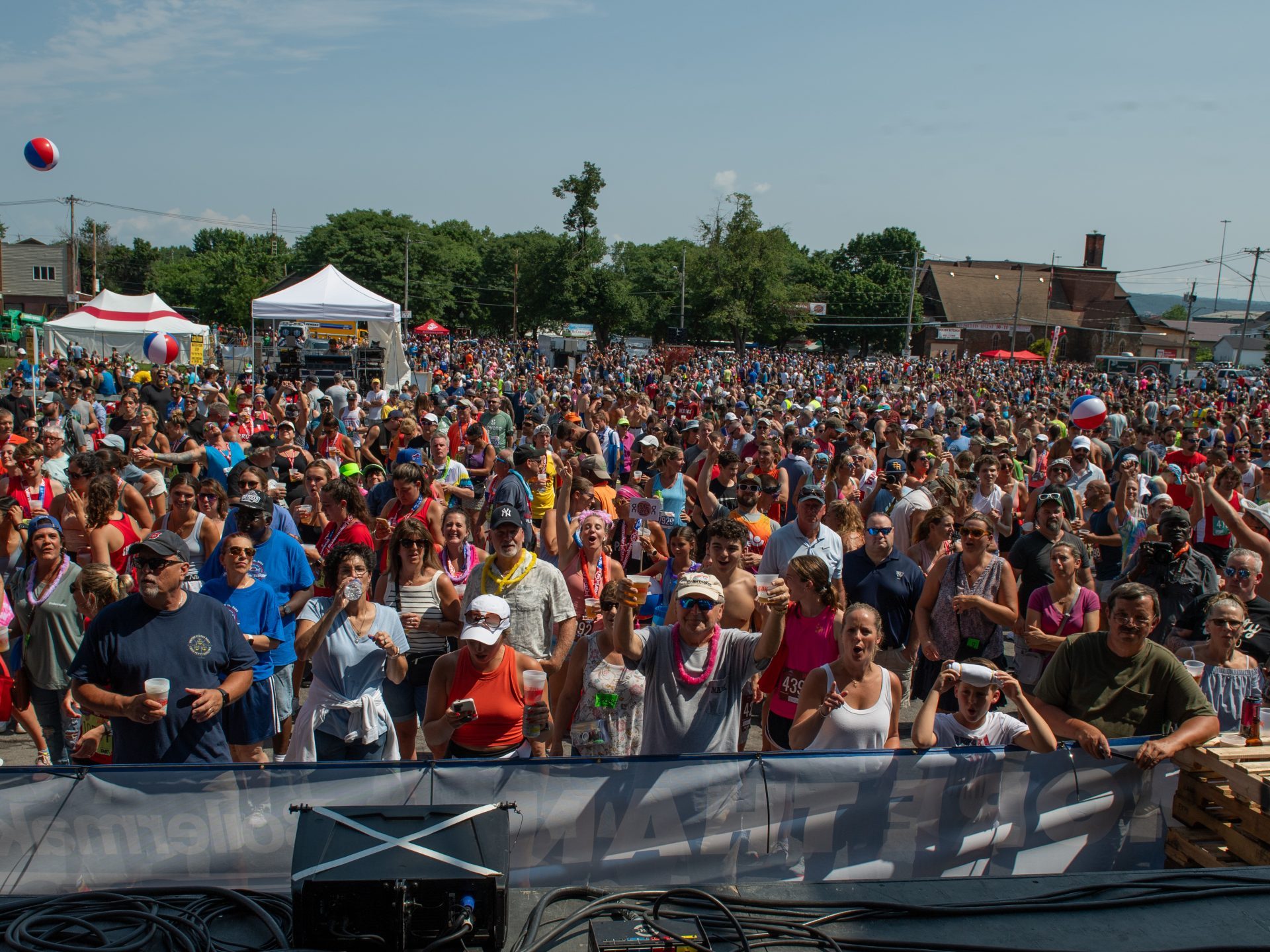 A crowd of people cheer looking up at the stage at the Boilermaker post-race party