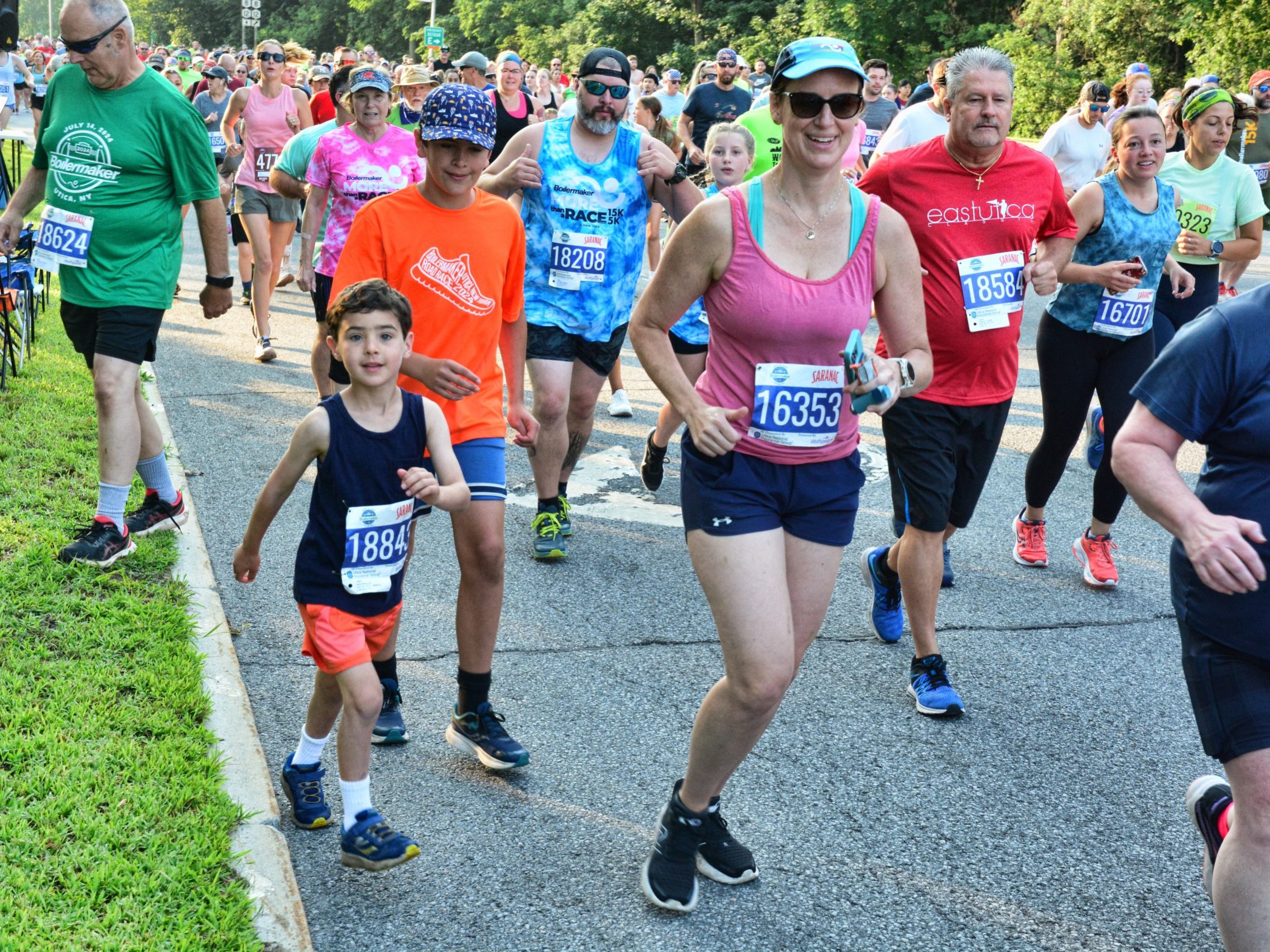 A group of runners smile and look to the camera along the 5K course