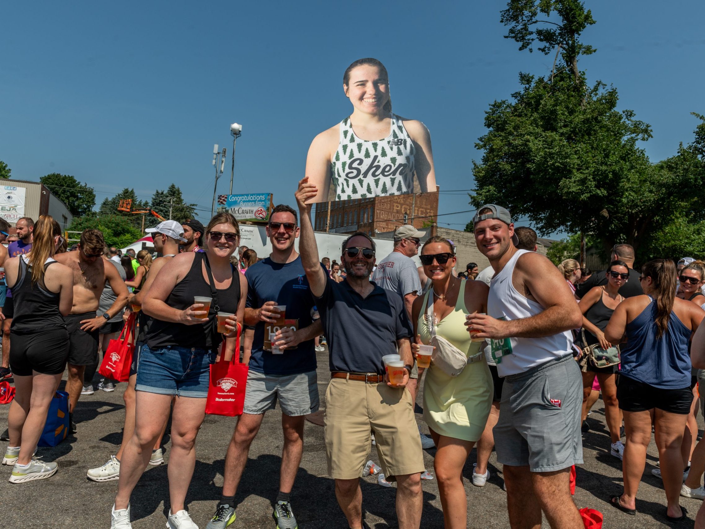 A group of post-race party goers hold up a cardboard cutout of their friend and pose for the camera