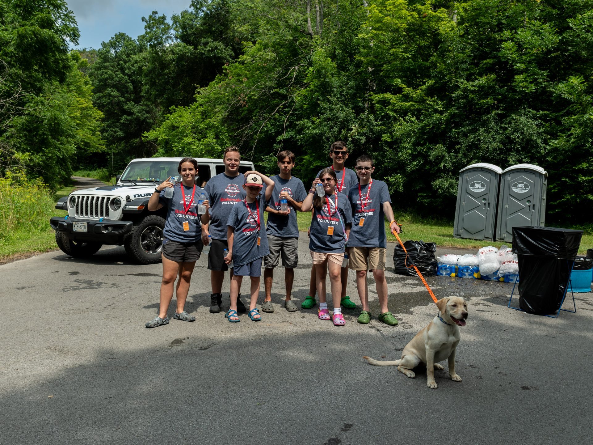 A group of volunteers and their dog hold bottled waters while waiting for Boilermaker walkers
