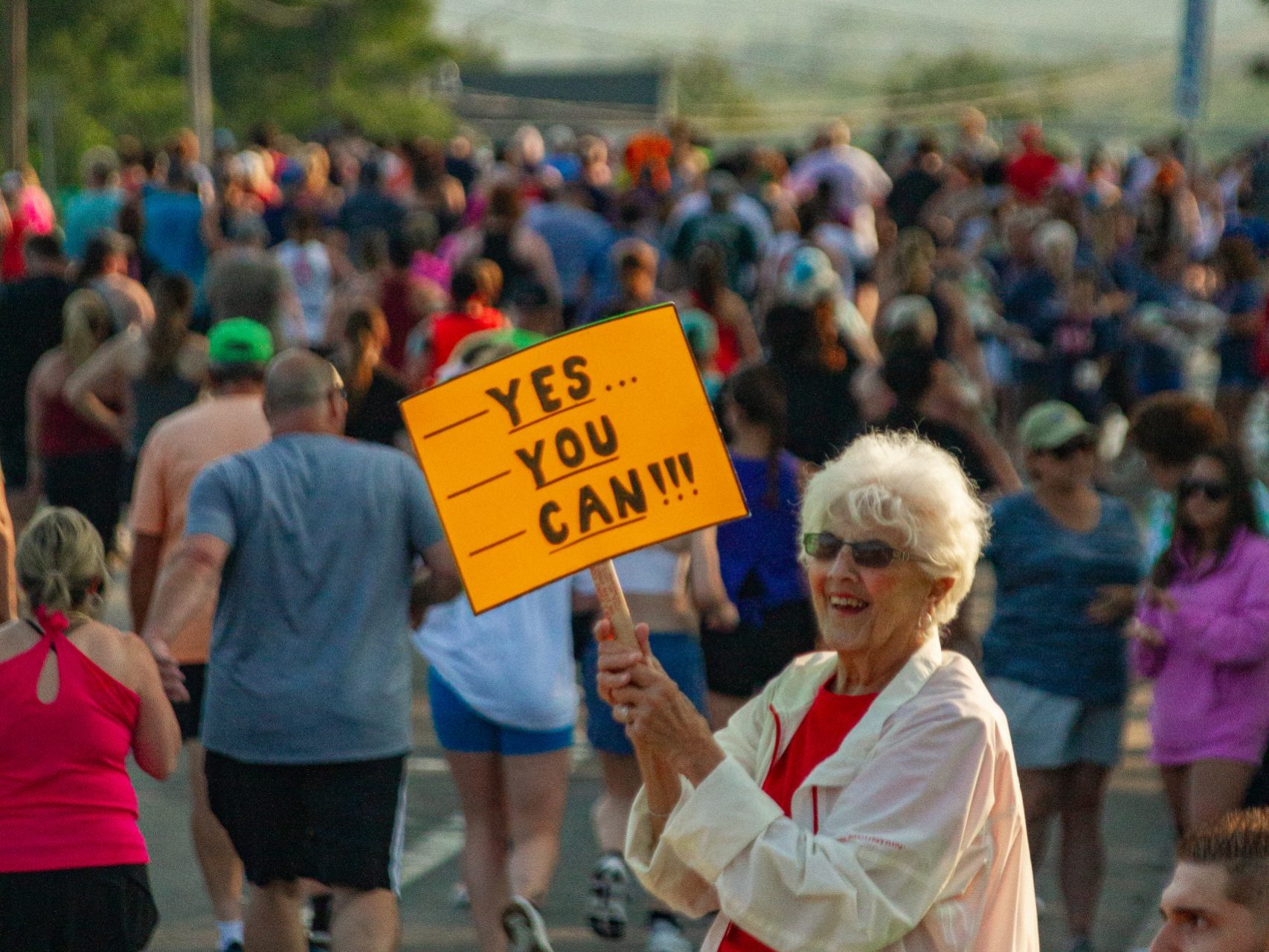 A woman holds up a "Yes You Can" sign as she cheers on Boilermaker 5K runners
