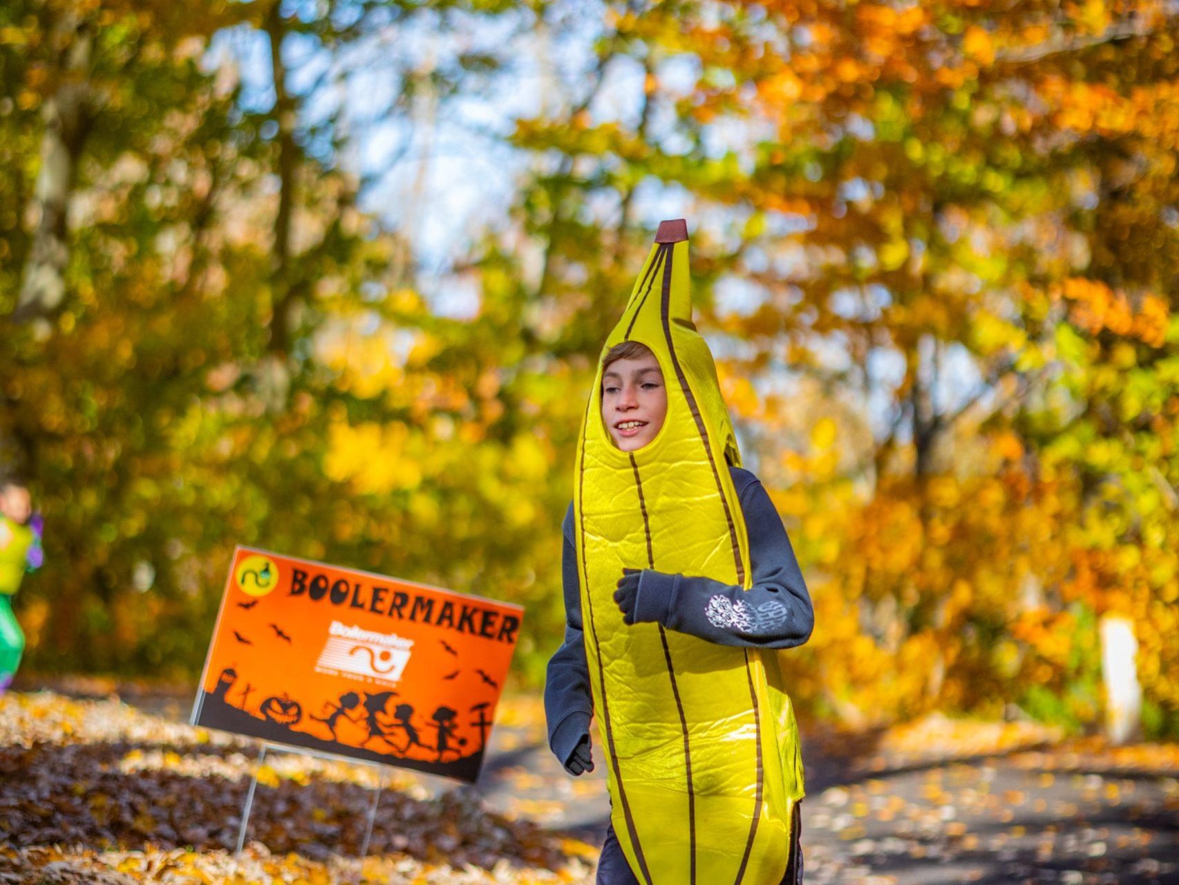 A boy in a banana costume runs through the trees